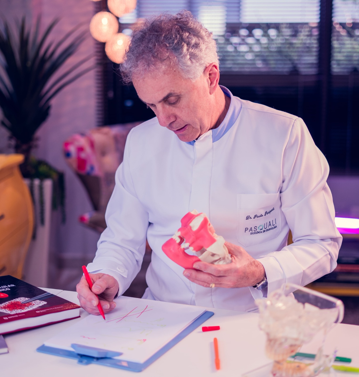 Dr. Paulo Pasquali, criador do Método TCO, em consultório segurando modelo anatômico de mandíbula